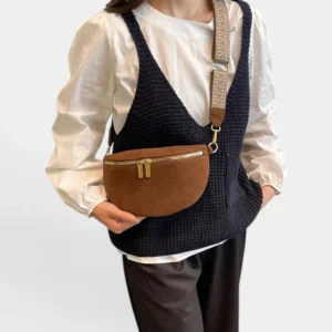 Sac banane marron en simili cuir porté en bandoulière par une femme, au style chic avec sangle à motifs