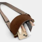 Sac banane en simili cuir marron, vu de face posé avec la poche principale ouverte laissant apparaître smartphone et cosmétiques