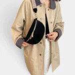 Sac banane simili cuir noir porté en bandoulière par une femme au style chic avec sangle à motif geometric