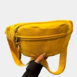 Sac banane en velours côtelé jaune vif, tenu en main de face avec zip tressé et sangle assortie