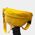 sac banane velours côtelé jaune posé de face tenu par une main, avec sangle tressée ton sur ton