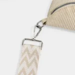 Sac banane velours côtelé beige vu de près, avec sangle à motif chevron et mousqueton en métal argenté