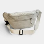 Sac banane velours côtelé beige posé de face, avec sangle écrue à boucle noire