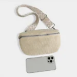 Sac banane velours côtelé beige posé vu de dessus, avec sangle motif chevron et smartphone posé devant