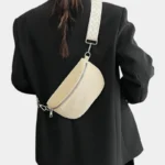 Sac banane velours côtelé beige porté en bandoulière par une femme de dos au style chic, avec sangle chevron