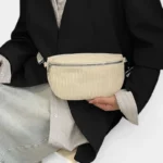 Sac banane en velours côtelé beige porté en bandoulière par une femme au style chic vue de face