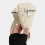 Sac banane velours côtelé beige tenu à la main, vu de côté avec sangle à motif géométrique