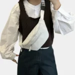 Sac banane velours côtelé blanc porté en bandoulière par une femme, avec sangle à motif noir