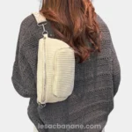 Sac banane velours côtelé écru porté en bandoulière dans le dos par une femme avec sangle jacquard à motif geométrique