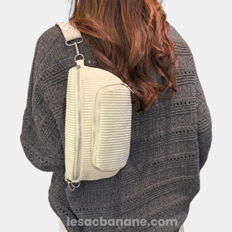Sac banane velours côtelé écru porté en bandoulière dans le dos par une femme avec sangle jacquard à motif geométrique