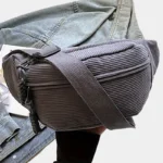 Sac banane velours côtelé gris ardoise posé de face, avec sangle large tressée ton sur ton