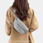 Sac banane velours côtelé gris porté en bandoulière par une femme de dos au style casual avec sangle motif chevron
