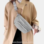 Sac banane velours côtelé gris porté en bandoulière par une femme avec sangle jacquard motif chevron