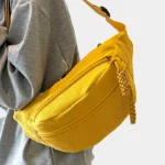 Sac banane velours côtelé jaune porté en bandoulière par une femme, vu de côté