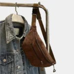 Sac banane velours côtelé marron posé en bandoulière sur un portant, vu de face avec sangle à clip plastique