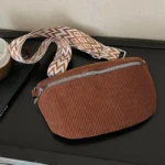 Sac banane velours côtelé marron posé à plat, vu de face avec sangle à motifs ethniques géométriques