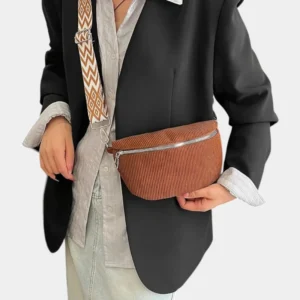 Sac banane velours côtelé marron porté en bandoulière par une femme au style chic, avec sangle à motif géométrique