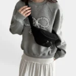 Sac banane velours côtelé noir porté en bandoulière par une femme, vue de face