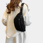 Sac banane noir en velours côtelé porté en bandoulière par une femme vu de dos