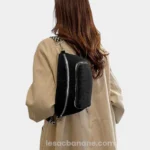 Sac banane velours côtelé noir porté sur l'épaule par une femme de dos