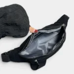 Sac banane velours côtelé noir posé de face, poche principale ouverte révélant une doublure grise contrastante