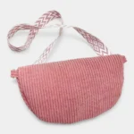 Sac banane velours côtelé rose posé face à plat, avec sangle jacquard à motif géométrique