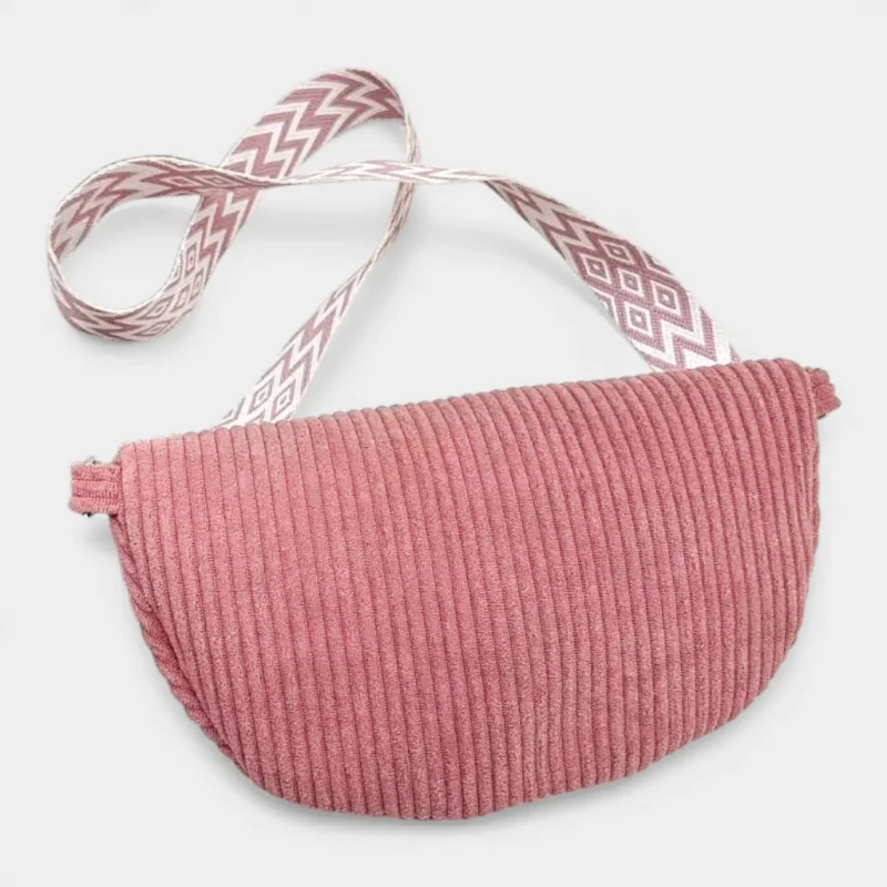 Sac banane velours côtelé rose posé face à plat, avec sangle jacquard à motif géométrique