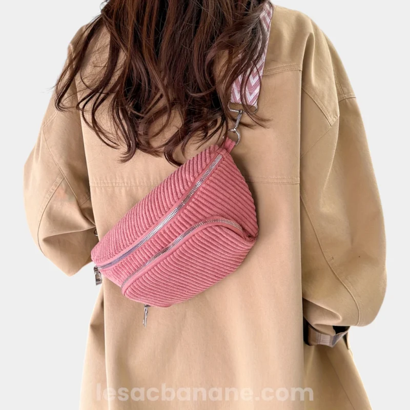 Sac banane velours côtelé rose porté en bandoulière par une femme au style casual avec sangle chevron