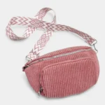 Sac banane velours côtelé rose posé de face, avec sangle jacquard à motif graphique blanc et rose