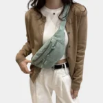 Sac banane velours côtelé vert porté en bandoulière par une femme de face avec un style casual chic