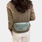 Sac banane velours côtelé vert pastel porté à la taille par une femme, vu de dos au style décontracté