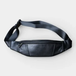 Petit sac banane cuir noir posé à plat, face avant avec fermeture éclair métallique et sangle en nylon