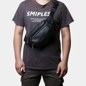 Sac banane cuir noir porté en bandoulière par un homme de face avec sangle à boucle plastique