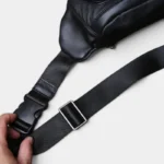 Sac Banane Cuir Noir Homme Souple Sac banane cuir noir homme souple posé de côté, gros plan sur la sangle réglable avec boucle plastique noire