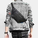 Grand sac banane cuir noir porté en bandoulière dans le dos par un homme au style rock vue arrière