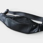 Petit sac banane cuir noir posé vu de dessus, poche principale ouverte révélant une poche zippée intérieure