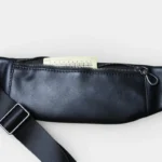 Petit sac banane cuir noir posé vue arrière, poche arrière ouverte contenant une carte