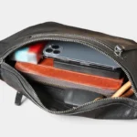 Grand sac banane cuir noir vu de dessus, poche principale ouverte révélant un smartphone et un portefeuille