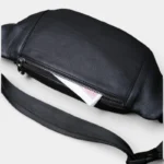 Sac Banane Cuir Noir Homme Souple Sac banane cuir noir posé de face, poche principale ouverte contenant des billets