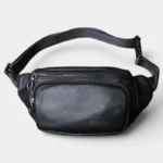 Sac Banane Cuir Noir Homme Souple Sac banane cuir noir posé de face, avec fermeture zippée métallique et sangle noire ajustable