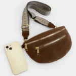Sac banane en simili cuir marron posé de face avec sangle à motif géométrique et un téléphone à côté