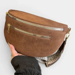 Sac banane marron en daim posé vu de face, avec sangle à motif tressé et fermetures zippées dorées