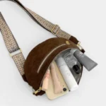 Sac banane en simili cuir marron vu de dessus, poche principale ouverte contenant smartphone et produits de beauté