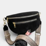 Sac banane noir en daim posé de face, avec large sangle à motif chevrons beige et attaches métalliques