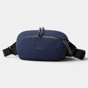 Sac banane nylon bleu marine au style gorpcore, posé de face avec des cordons tressés gris sur la fermeture