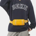 Petit sac banane nylon jaune porté à la taille par un homme de face au style streetwear