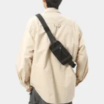 Petit sac banane nylon noir porté en bandoulière dans le dos par un homme, vue de dos
