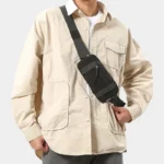 Petit sac banane nylon noir porté en bandoulière par un homme, au style workwear décontracté