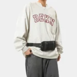 Petit sac banane nylon noir porté à la taille par un homme de face au style streetwear