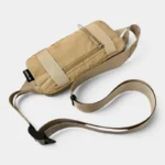 Petit sac banane nylon beige sable posé à plat en vue de dessus, avec sangle réglable à boucle plastique